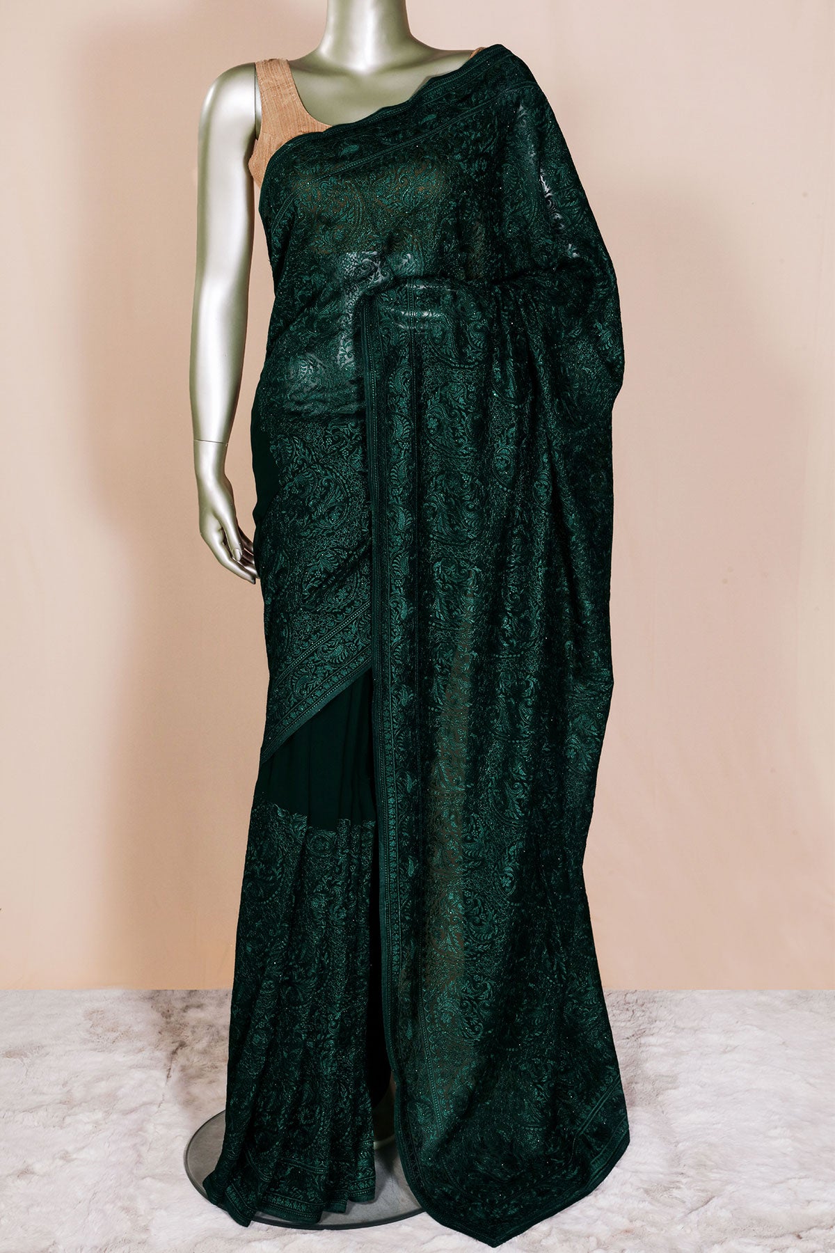 Dark green saree on a mannequin against a beige background