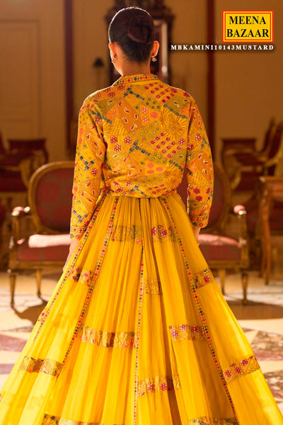 Person wearing a yellow traditional outfit with floral patterns in a room setting, branded 'Meena Bazaar'.